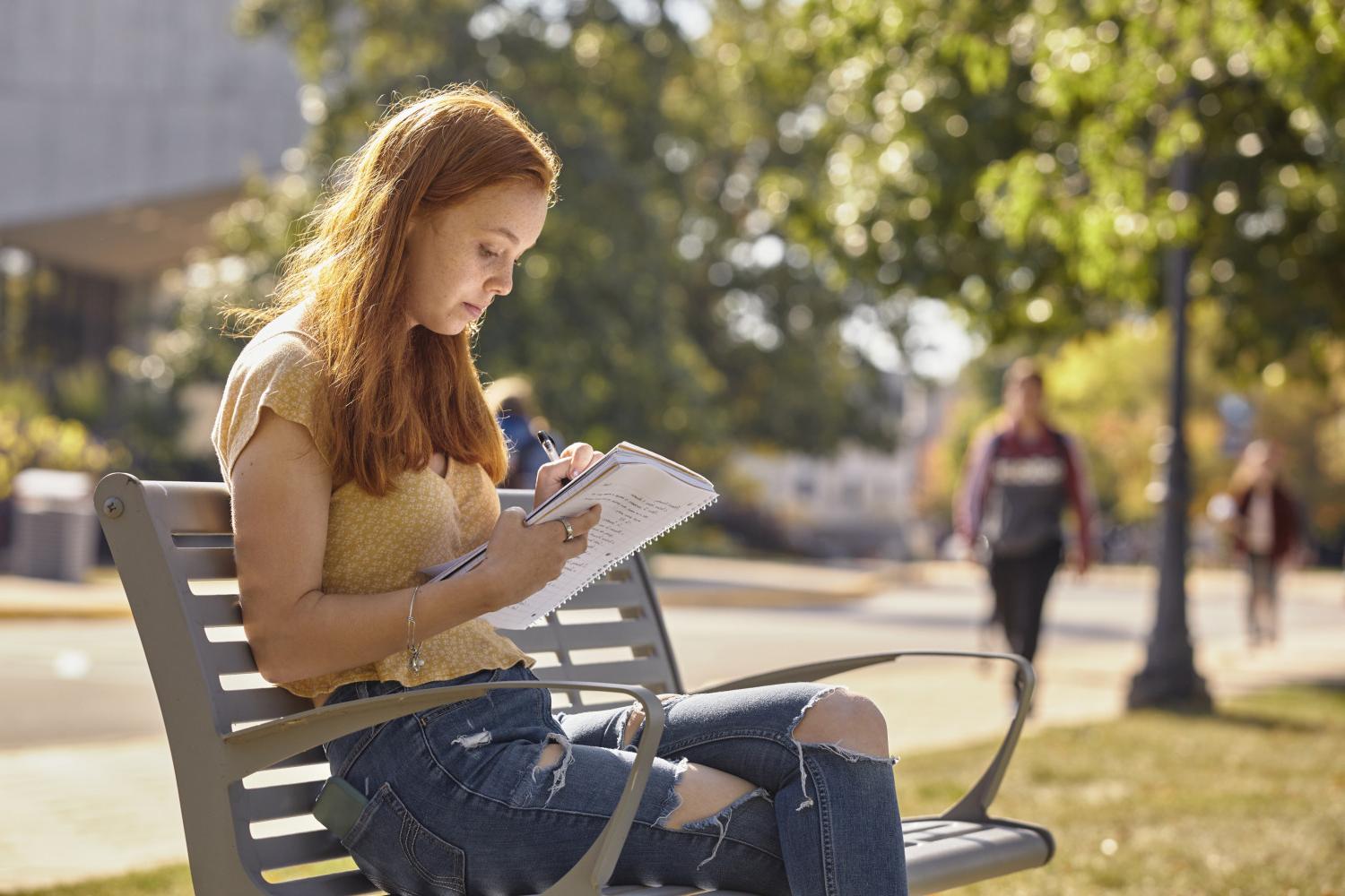 一位<a href='http://eqbd.cl0907.com'>全球十大赌钱排行app</a>学院的学生在校园里的长椅上读书.